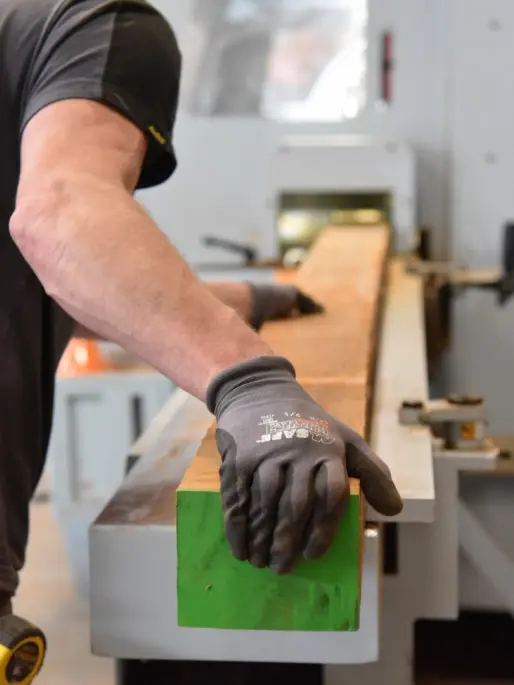 Houten balk wordt geschaafd in de werkplaats van Grijsen